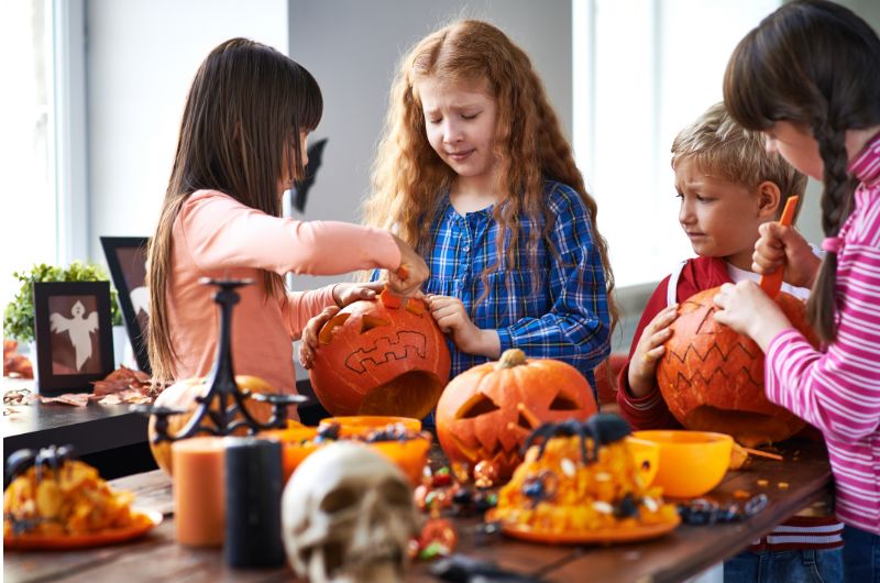 Children carve a Jack O'Lantern pumpkin